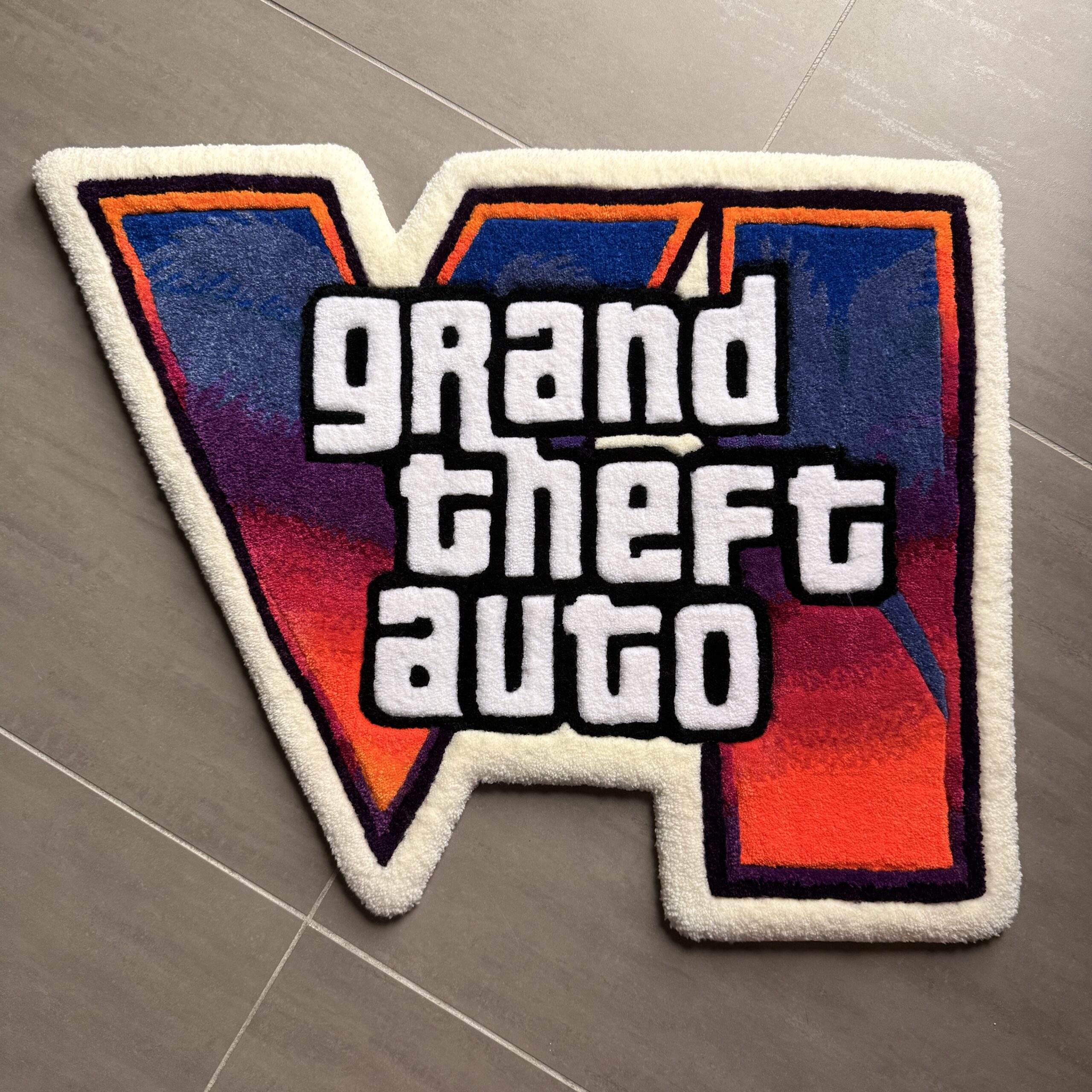 Tapis tufté GTA 6 fait main avec logo coloré sur fond bleu, rouge et orange
